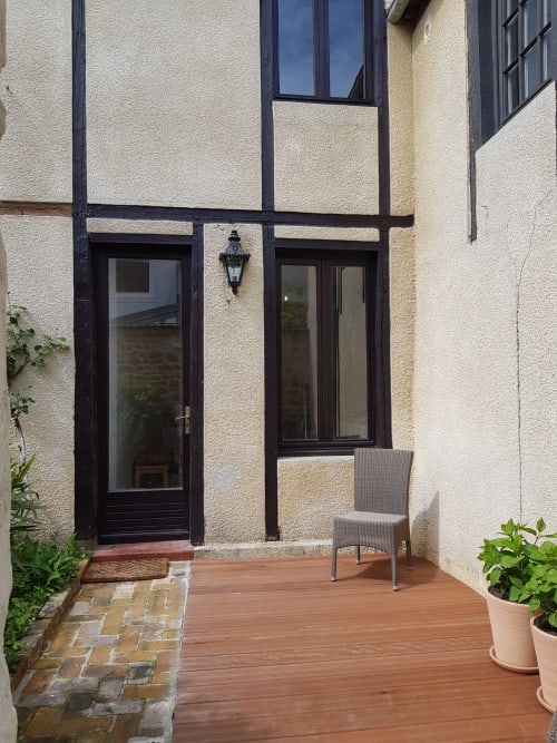 Entrée de terrasse de l'hôtel Les Cabines à Houlgate avec porte noire, terrasse en bois et plantes en pots