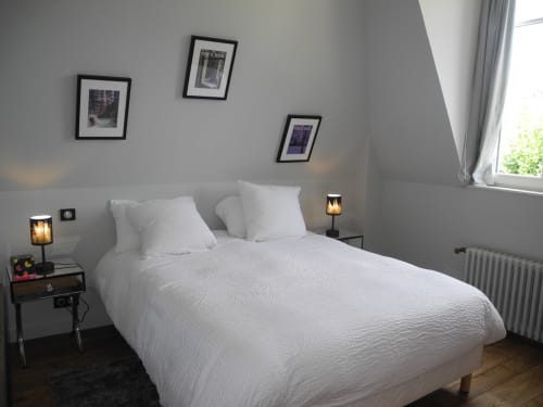 Modern bedroom at Le château d'Hermonville B&B in Hermonville with white bedding, framed artwork, and warm bedside lighting.