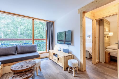 Appartement moderne à Arc 1800 Bellecôte : séjour, TV écran plat, mobilier bois, balcon vue forêt