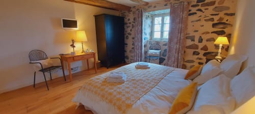 Chambre zen au Mas De Rigoulac avec vue sur le jardin, lits doubles, bureau en bois, murs en pierre et éclairage chaleureux