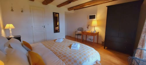 Chambre zen au Mas de Rigoulac avec poutres apparentes, lit queen-size, mobilier en bois et vue sur le jardin à Argences-en-Aubrac