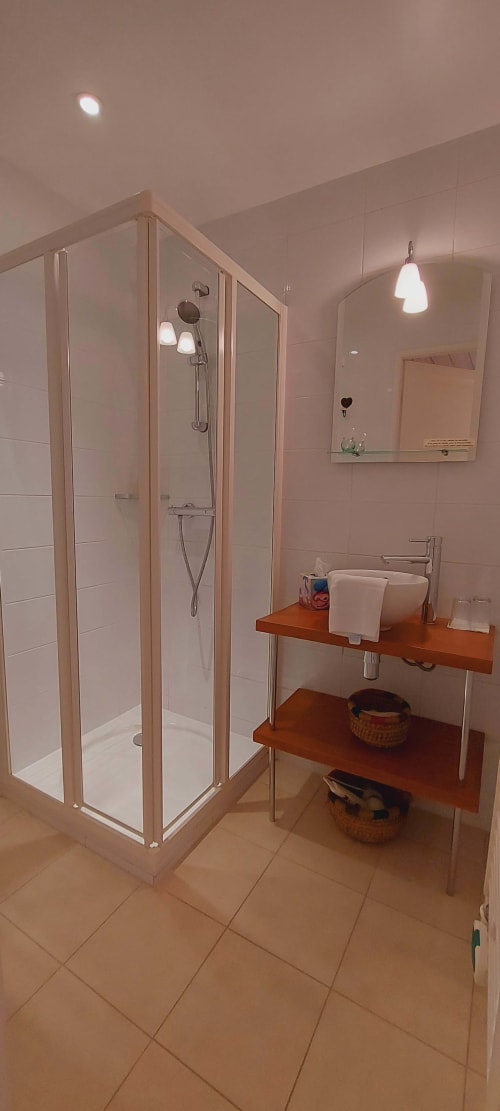 Salle de bain moderne au Mas De Rigoulac avec douche d'angle, étagères en bois et luminaires suspendus