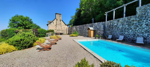 L'espace piscine du Mas de Rigoulac avec sa demeure en pierre, transats et jardins à Argences-en-Aubrac