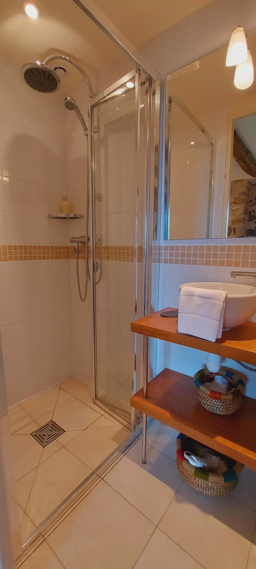 Salle de bain moderne avec cabine de douche en verre, sèche-serviettes électrique et vasque en bois au Mas De Rigoulac à Argences-en-Aubrac