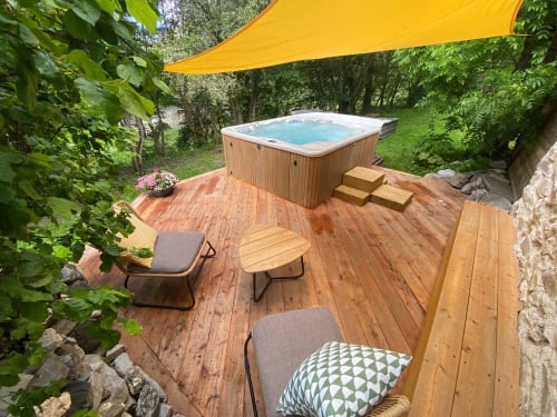 Bain à remous sur terrasse en bois avec parasol jaune à la maison d'hôtes Les Méans à Meolans-Revel, France