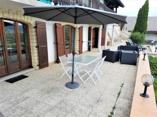 Terrasse avec table et parasol, gîte en haute Savoie. 