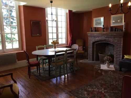 Elegant dining and living room at La Chatellenie apartment in Saint Aubin, with fireplace, wooden floors, and period