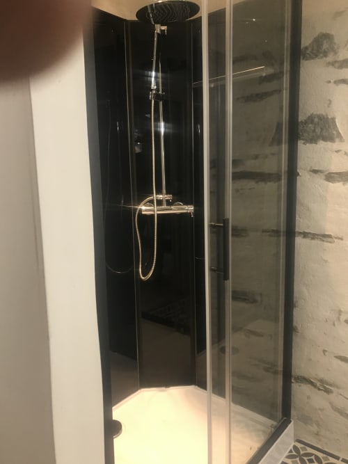 Élégante douche avec panneaux noirs et accessoires chromés dans le gîte La Bergerie du Petit Manoir de Kériolet