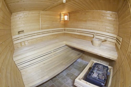 Interior of a wooden sauna with tiered benches and heated stone stove at Espace Ker Gana B&B in Plourin, France