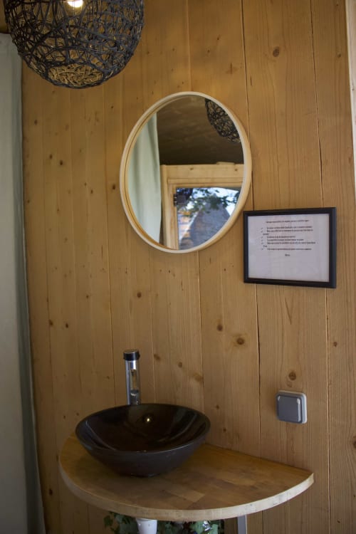 Rustic wooden bathroom sink with black bowl and oval mirror at Espace Ker Gana, Plourin