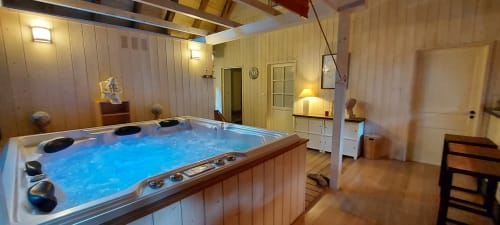 Bain à remous aux eaux bleues dans une suite zen aux murs en bois au Mas De Rigoulac, Aubrac France