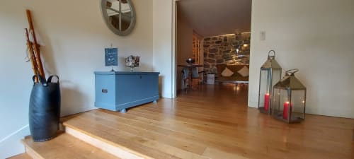 Entrée de la Chambre Nuage au Mas De Rigoulac avec parquet, coffre bleu, lanternes et vue sur la cheminée en pierre