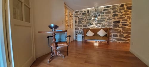 Chambre accueillante aux murs de pierre, planchers de bois, canapé cuir brun et mobilier moderne au Mas De Rigoulac