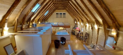 Spacieuse chambre loft au Mas De Rigoulac avec poutres apparentes, mobilier blanc et vue sur le jardin en Aubrac