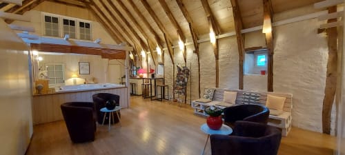 Salon rustique moderne au Mas de Rigoulac : poutres bois apparentes, sièges anthracite, réception, pierres blanchies