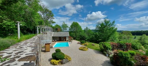 Vue du jardin du Mas de Rigoulac avec piscine commune et terrains paysagés à Argences-en-Aubrac