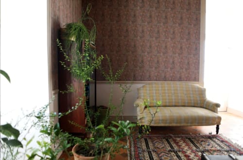 Cozy seating area at Château Le Breuil with striped sofa, hanging plants, and patterned wallpaper in Chaillac