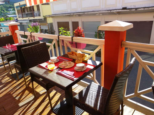 Terrasse ensoleillée de l'Hôtel du Cirque à Cilaos avec parasols colorés et petit-déjeuner