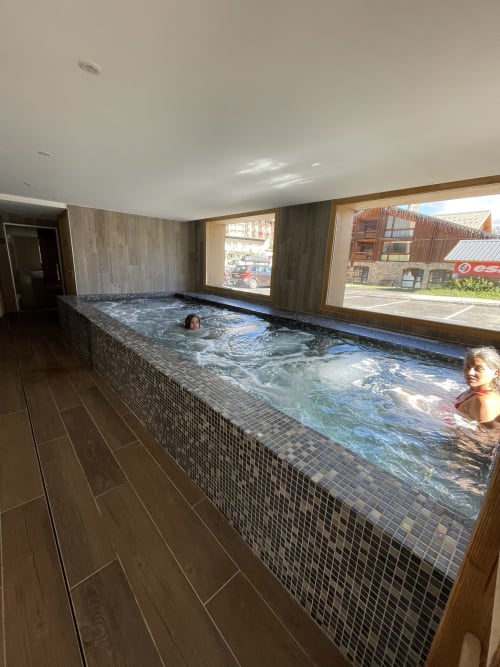 Indoor swimming pool at Le château d'Hermonville with guests enjoying heated waters, mosaic tile design, and large windows