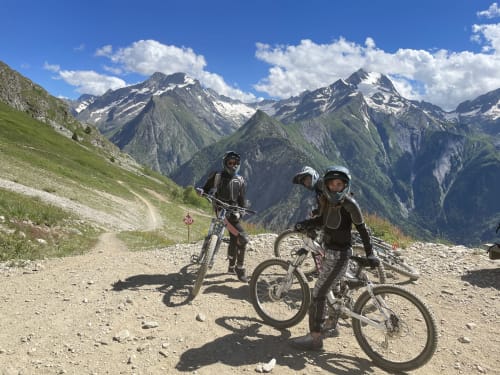 Trois cyclistes casqués sur un sentier montagnard avec vue sur les pics alpins près d'Hermonville, France