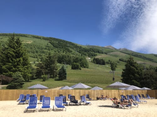 Beach club at Le château d'Hermonville with blue loungers, umbrellas, and green hills in Hermonville, France