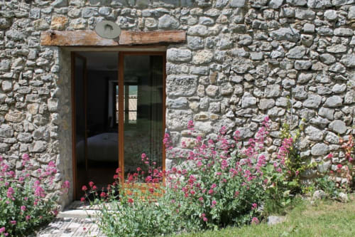 Entrée de maison en pierre avec fleurs roses à la maison d'hôtes Entre Terre Et Ciel à Rémuzat