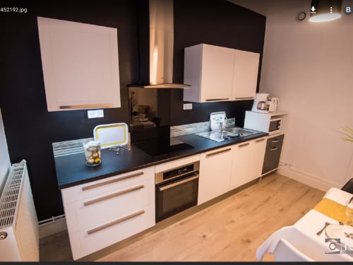 Cuisine moderne blanche avec plan de travail noir, four intégré et dosseret foncé à la Villa 13, Mers-les-Bains