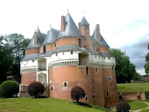 Château historique en brique rouge avec tourelles et jardins soignés à Mers-les-Bains, France