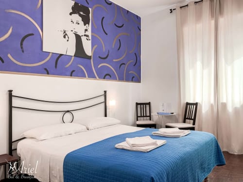 Ariel Bed & Breakfast bedroom in Verona with blue bedspread, black metal bed frame, purple wall art, and modern furnishings.