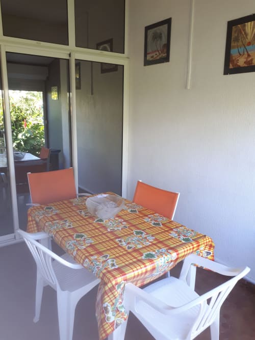 Studio apartment dining area with white chairs, colorful tablecloth, and glass doors overlooking garden at Studio Face
