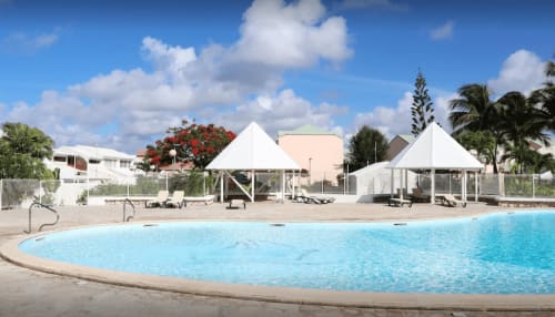 Studio Face Marina pool in Saint-François with tropical landscape, white cabanas, and lounge chairs