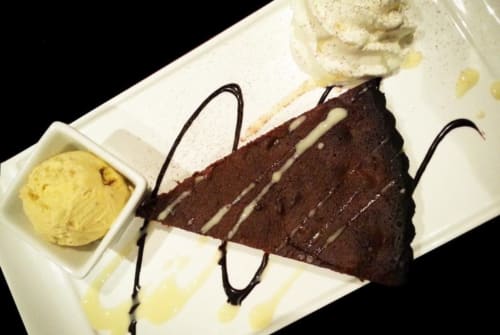 Tranche de gâteau au chocolat avec glace à la vanille et coulis à l'hôtel La Consigne, Caen