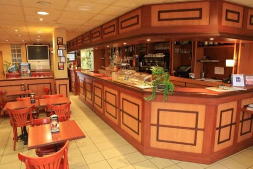 Hôtel café La Consigne à Caen avec comptoir en bois orangé, salle à manger et comptoir de service avec articles exposés