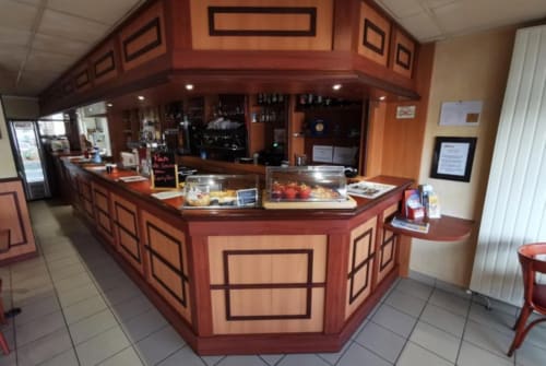 Le bureau de réception de l'hôtel La Consigne à Caen avec comptoir en bois et vitrine de pâtisseries