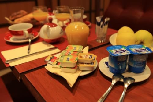 Table du petit-déjeuner de l'hôtel La Consigne avec beurre, yaourt, jus et citrons frais à Caen