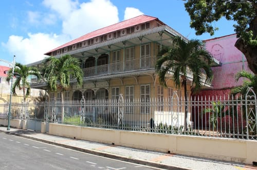 Bâtiment historique colonial Studio Face Marina aux toits rouges, clôture blanche et palmiers à Saint-François, Guadeloupe