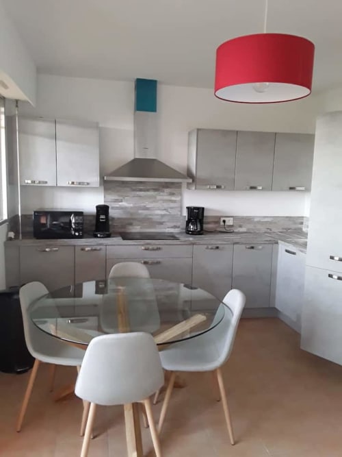 Cuisine-salle à manger moderne à Ajaccio avec meubles gris, luminaire suspendu rouge et table à manger en verre