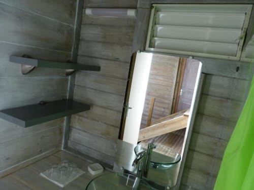 Interior del bungalow en Le Bougainvillier Blanc, Pointe Noire con paredes de madera, espejo, repisa y aire acondicionado