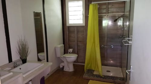 Modern bathroom in Bungalow 2 at Le Bougainvillier Blanc, Pointe Noire, featuring shower, toilet, sink, and yellow curtain