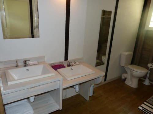 Shared bathroom in Bungalow 2 at Le Bougainvillier Blanc, Pointe Noire, featuring dual sinks, toilet, and shower facilities