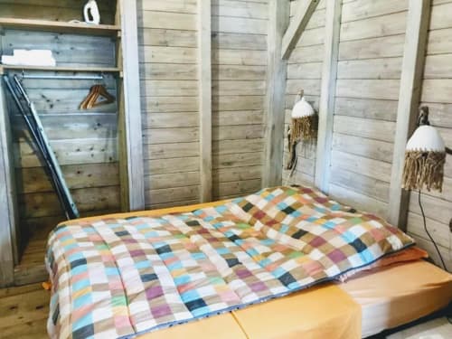 Colcha de retazos colorida en cama de madera en el bungalow Le Bougainvillier Blanc en Pointe Noire, con paredes de madera rústica