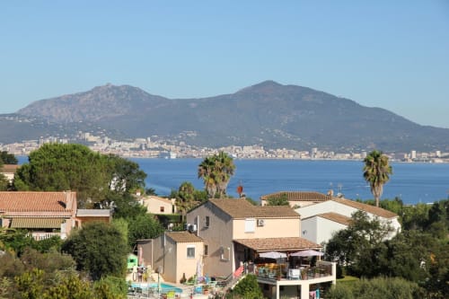 Gîte corse avec vue sur mer dominant la côte méditerranéenne, les montagnes et la petite ville côtière