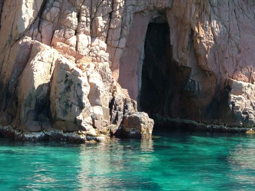 Entrée de grotte marine aux eaux turquoise, formations rocheuses côtières et caverne naturelle de Corse