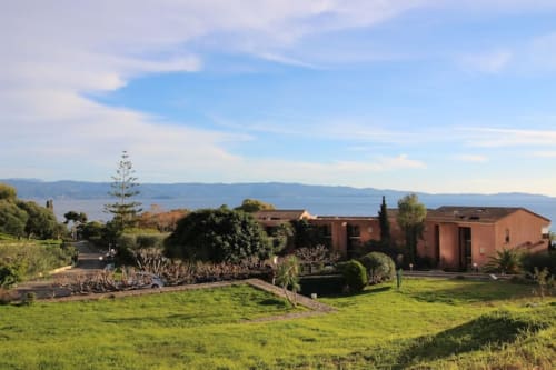 Gîte corse authentique avec bâtisses en terre cuite, jardins soignés et vue sur la Méditerranée
