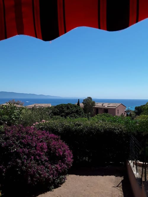 Villa corse avec vue sur mer, jardin de bougainvillées violettes, paysage méditerranéen et ciel bleu dégagé
