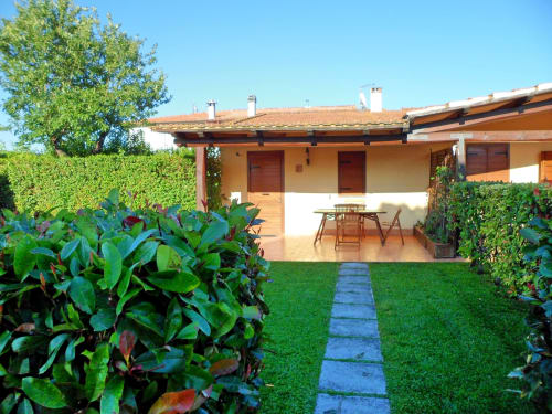 Cortile del Podere Oca Bianca B&B a Pescia Romana con patio in terracotta, vialetto in pietra e rigogliosi giardini verdi