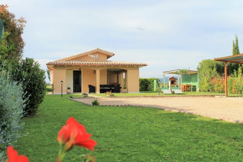 Podere Oca Bianca B&B a Pescia Romana: villa in cotto, prato curato, fiori rossi e vista sulla campagna
