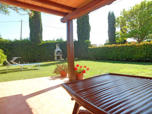 Patio con vista giardino a Podere Oca Bianca con pergolato in legno, sdraio e fiori in fiore con vista sui verdi prati