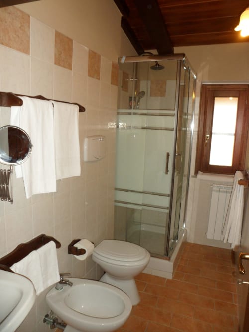 Bagno moderno a Podere Oca Bianca con doccia in vetro, doppio lavabo e pavimenti in cotto