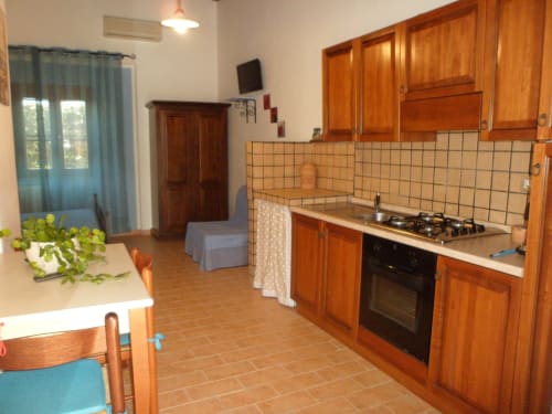 Cucina e zona pranzo Azalea a Podere Oca Bianca con arredamenti in legno e vista sul giardino